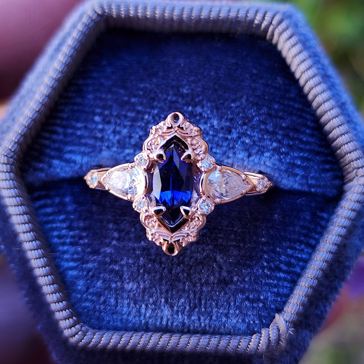 Rose gold filigree ring with a blue sapphire marquise gemstone in a blue velvet box image 1