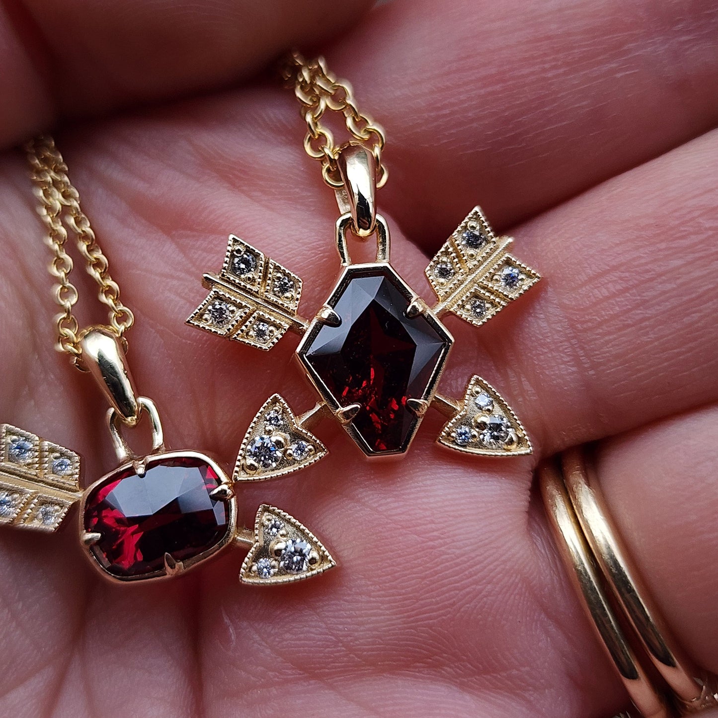 Gold necklace with garnet stones held in a hand