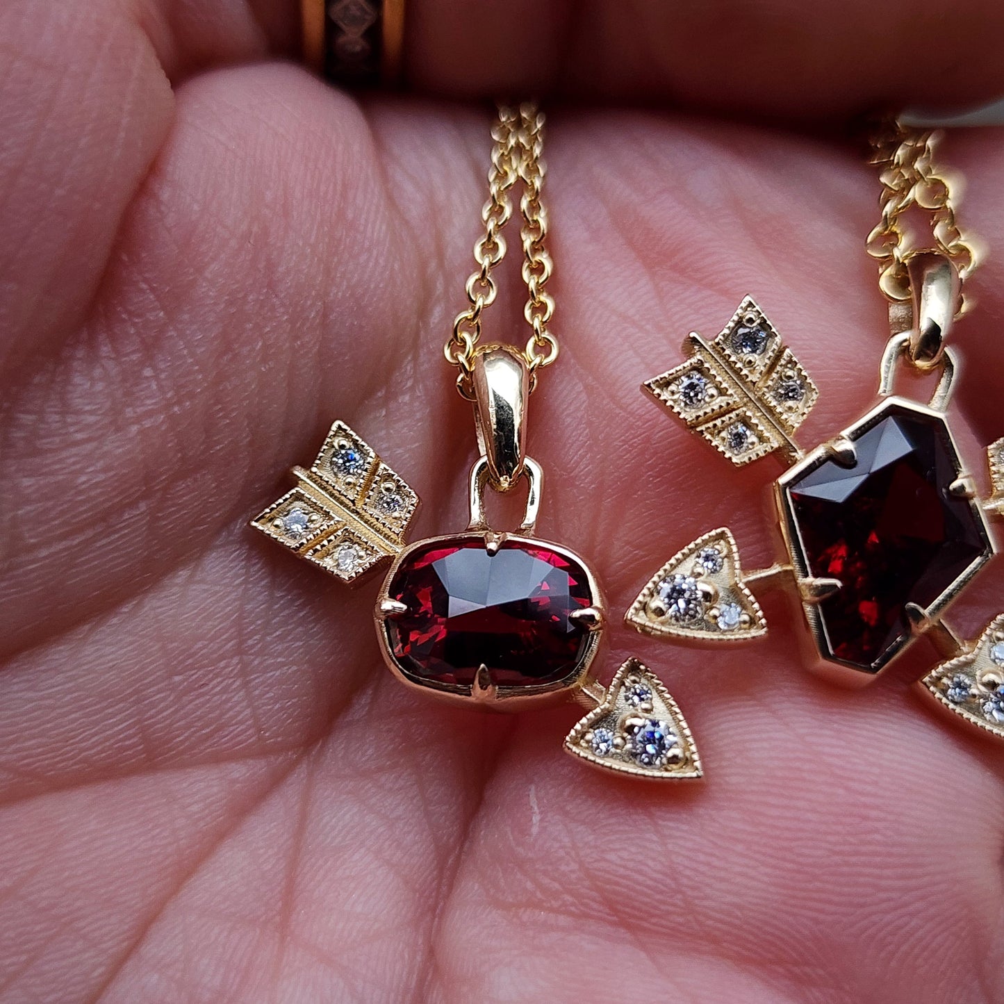 Gold necklace with a red gemstone pendant held in hand