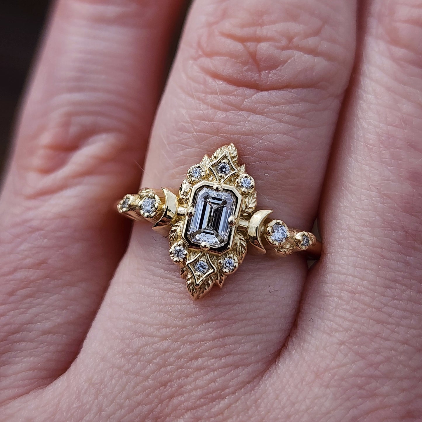 Elegant, and nature-inspired design, this ring features a delicate leaf motif and crescent moons, all crafted in 14kt yellow gold The center stone is a .30 carat natural emerald-cut diamond image 8