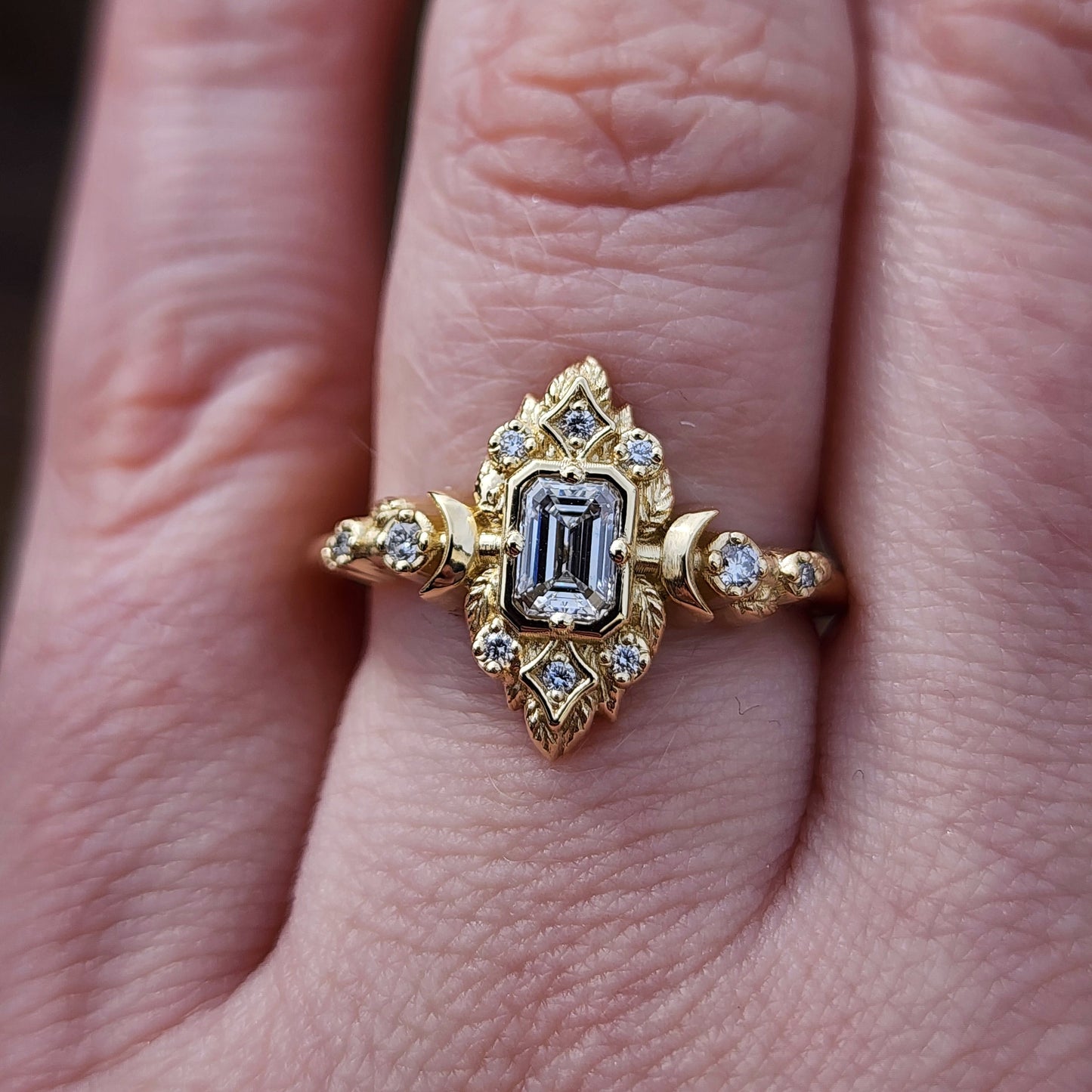 Elegant, and nature-inspired design, this ring features a delicate leaf motif and crescent moons, all crafted in 14kt yellow gold The center stone is a .30 carat natural emerald-cut diamond image 9