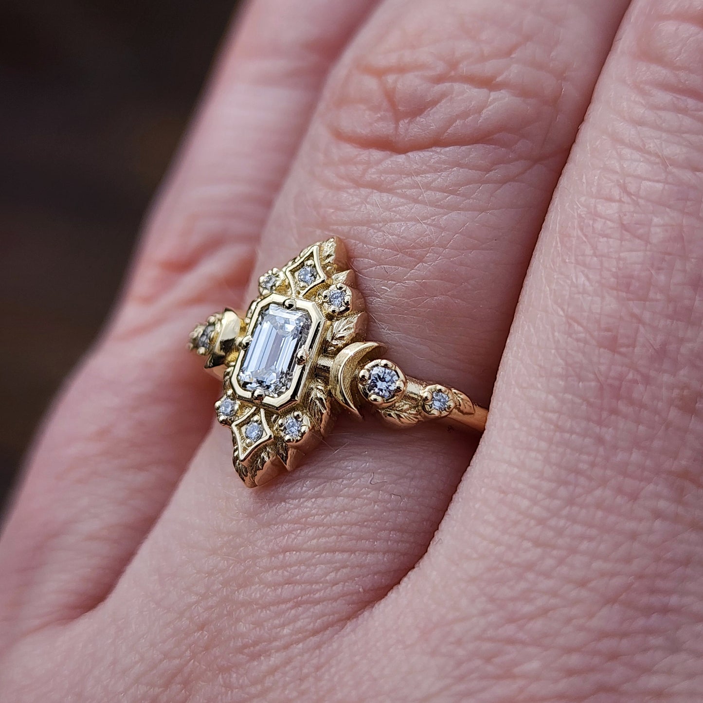 Elegant, and nature-inspired design, this ring features a delicate leaf motif and crescent moons, all crafted in 14kt yellow gold The center stone is a .30 carat natural emerald-cut diamond image 11