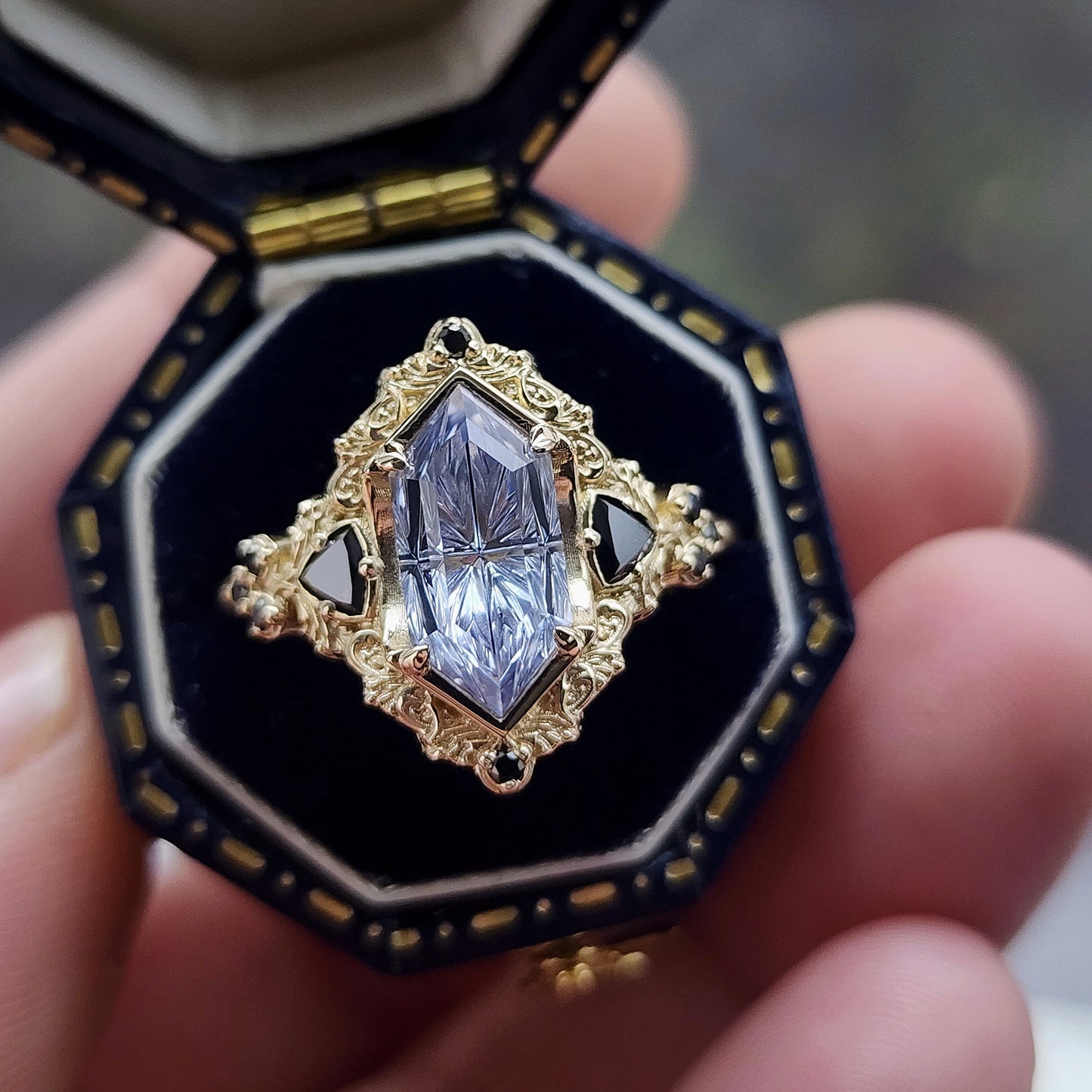 Ophelia/Delilah hybrid ring features a 2.92ct Light Purple Lab Sapphire Fantasy Cut from Fellowship Forge. The ring is accented with black diamond trillions totaling .18cts and additional black diamond accent stones totaling .07cts Crafted in 14kt yellow gold image 1