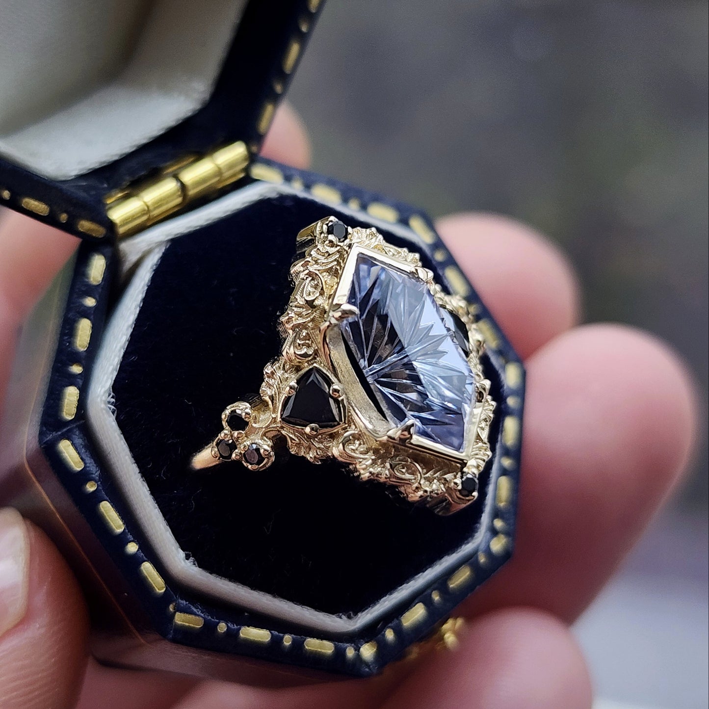 Ophelia/Delilah hybrid ring features a 2.92ct Light Purple Lab Sapphire Fantasy Cut from Fellowship Forge. The ring is accented with black diamond trillions totaling .18cts and additional black diamond accent stones totaling .07cts Crafted in 14kt yellow gold image 2