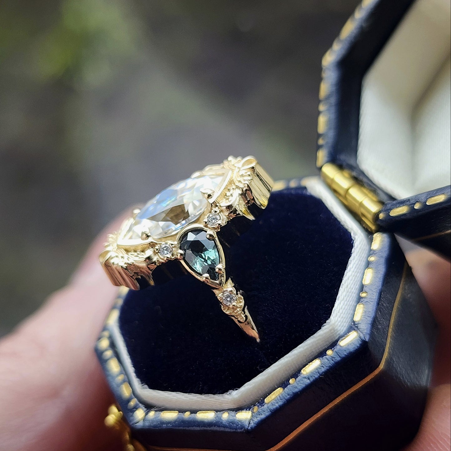 This Odette ring is a stunning piece, centered around a striking 1.20ct Moissanite Marquise, featuring an Old Mine Cut This center stone is beautifully complemented by Natural Australian Pear Sapphires, totaling .43ct, and accented with .05ct VS natural white diamonds Crafted in 14kt yellow gold image 2