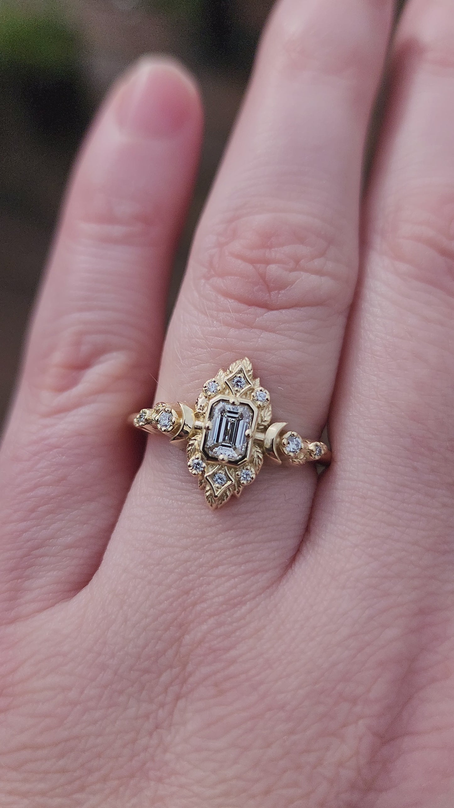 Load and play video in Gallery viewer, Elegant, and nature-inspired design, this ring features a delicate leaf motif and crescent moons, all crafted in 14kt yellow gold The center stone is a .30 carat natural emerald-cut diamond video 1
