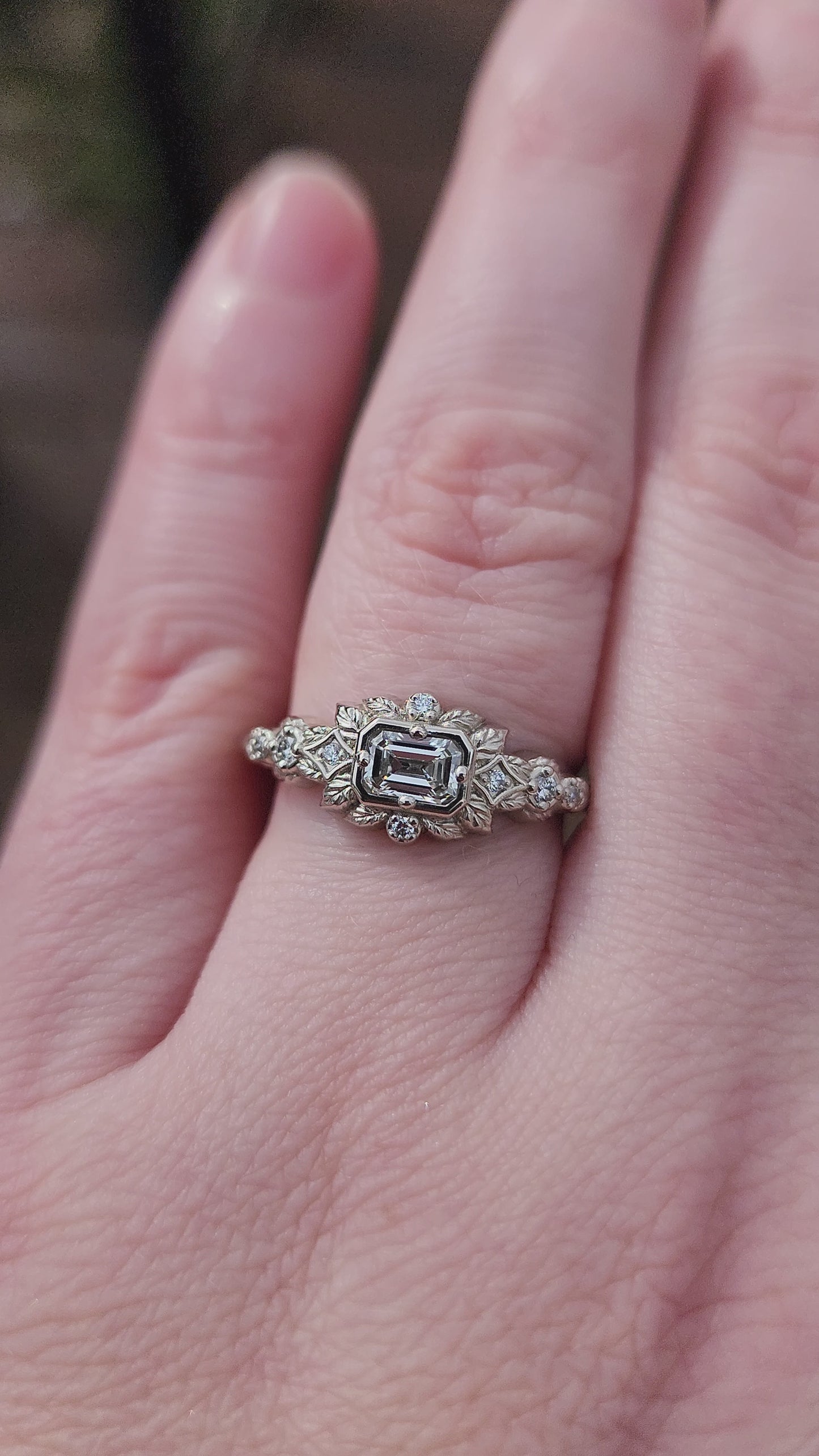 Load and play video in Gallery viewer, nature-inspired ring , featuring a .32 carat natural emerald-cut diamond set in an east-west orientation. The delicate leaf motif is crafted in 14kt palladium white gold video 1
